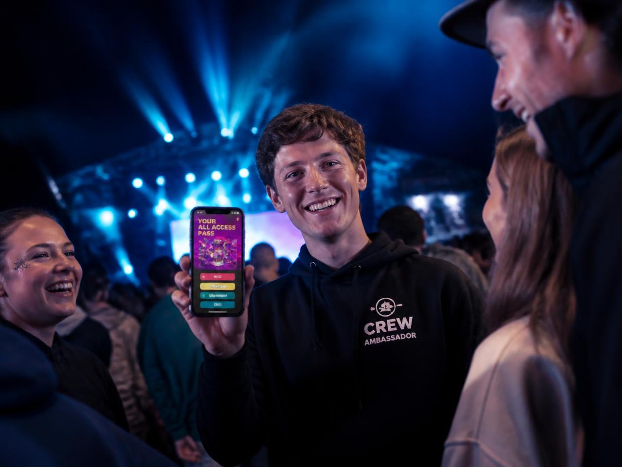 Ambassadeur laat de AmbassaHub-app zien aan vrienden op een festival